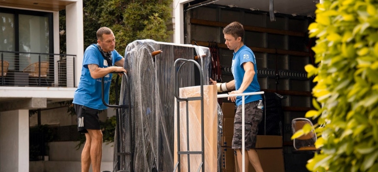Two movers lifting items into a moving truck