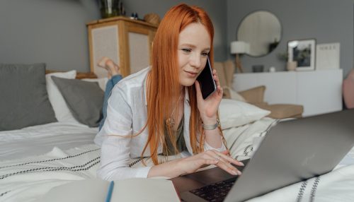 Girl on the bed with a phone and a laptop