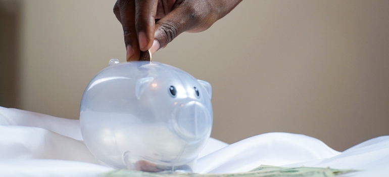 a person putting a coin in a piggy bank after moving from San Francisco to Phoenix