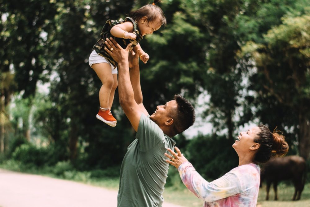 smiling parents throwing their baby