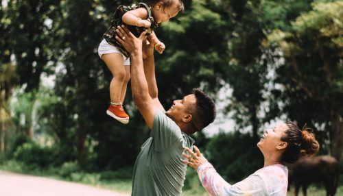 smiling parents throwing their baby