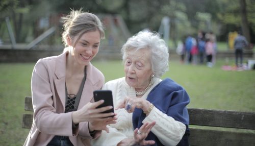 A young woman showing her elderly mother something on the phone.