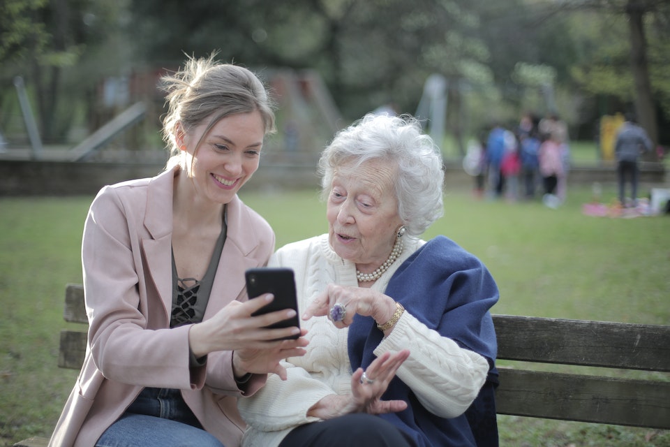 A young woman showing her elderly mother something on the phone.