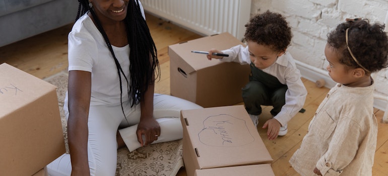 A mom with two kids labeling boxes while thinking about Las Vegas to Los Angeles move made simple;