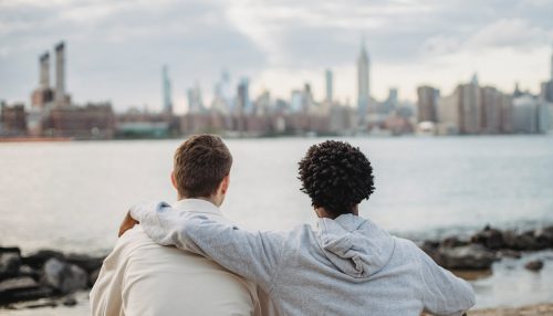 Two friends watching a city across the river.