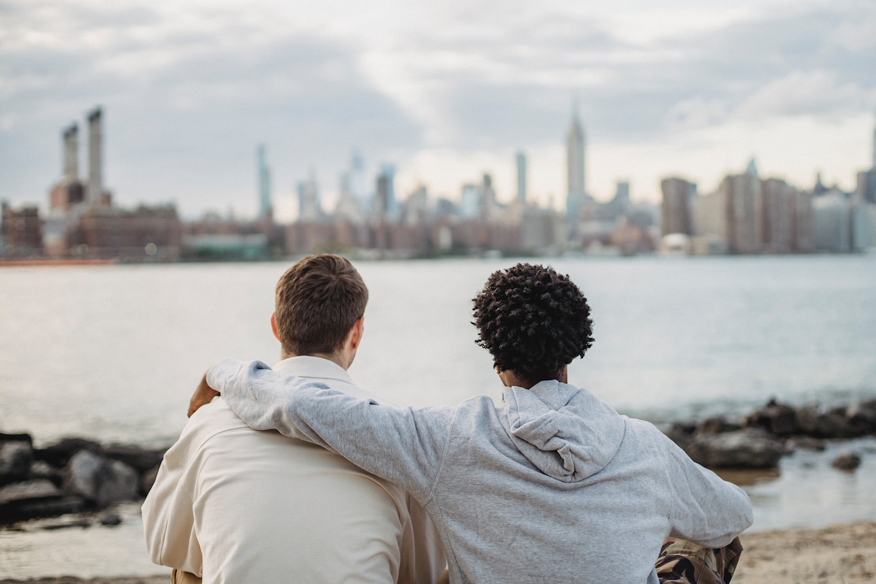 Two friends watching a city across the river.
