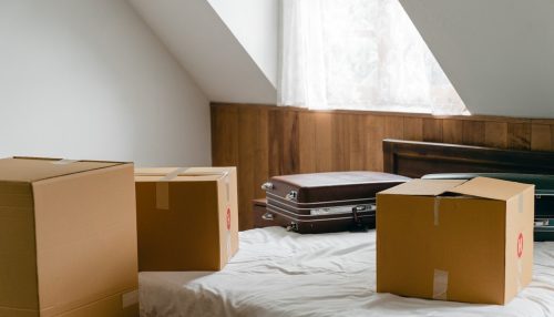 cardboard boxes and suitcases on a bed