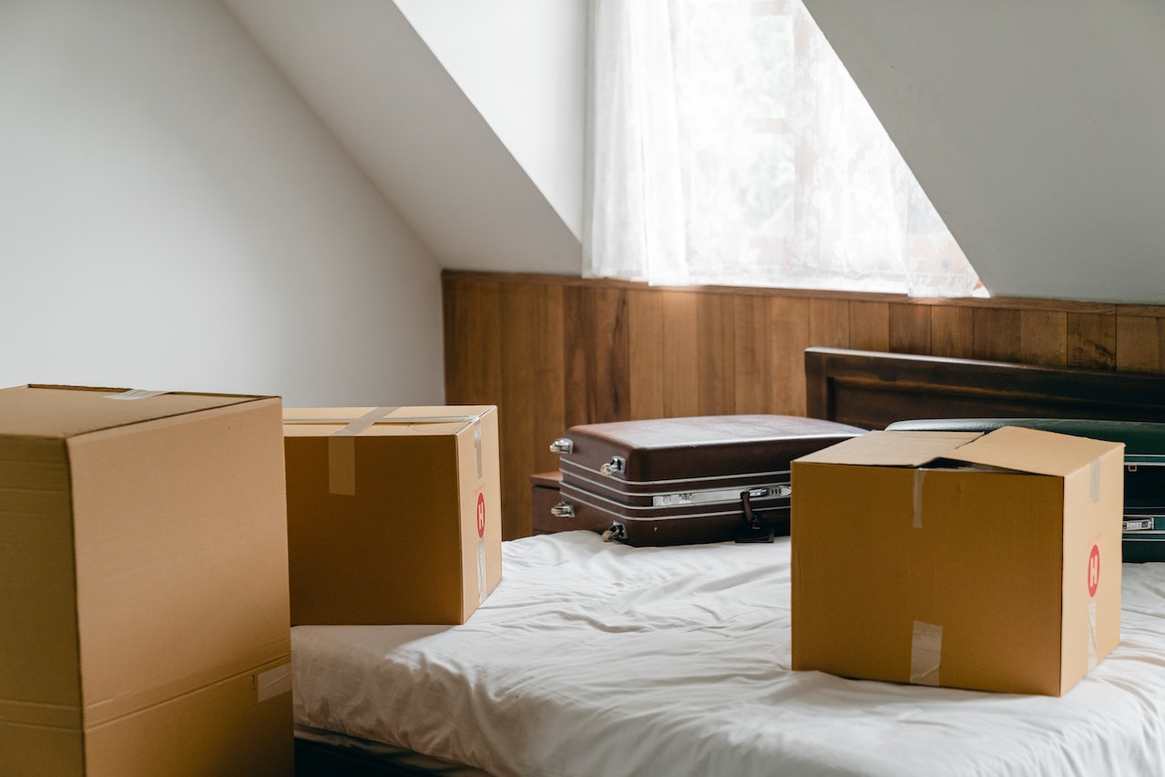 cardboard boxes and suitcases on a bed