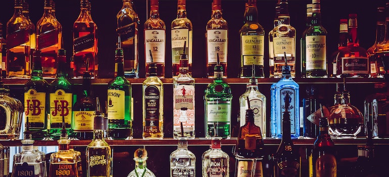 Sorted bottles of liquor on a bar shelf;