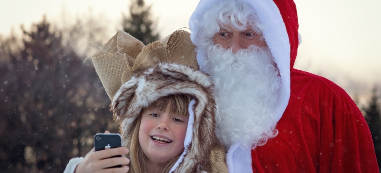 A kid making a selfie with Santa Claus for Christmas 2022/2023