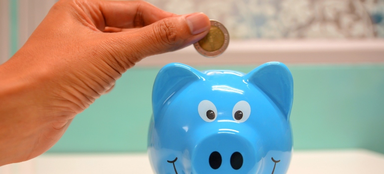 person putting money in piggy bank as saving is what you need to know about renting in California