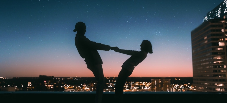 A couple holds hands romantically on the roof of a building at the night