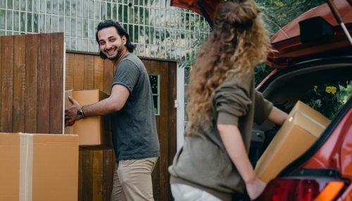 Happy couple unloading automobile with moving boxes