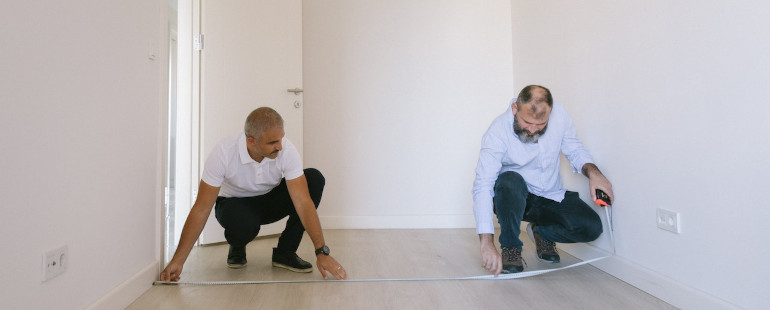 Two men measuring a room