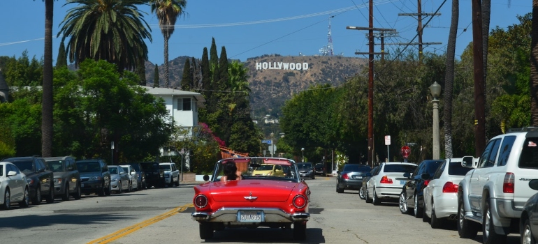 A red car and a Hollywood sign in the background